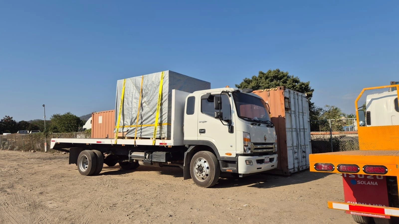 Camión de plataforma con carga asegurada en patio industrial